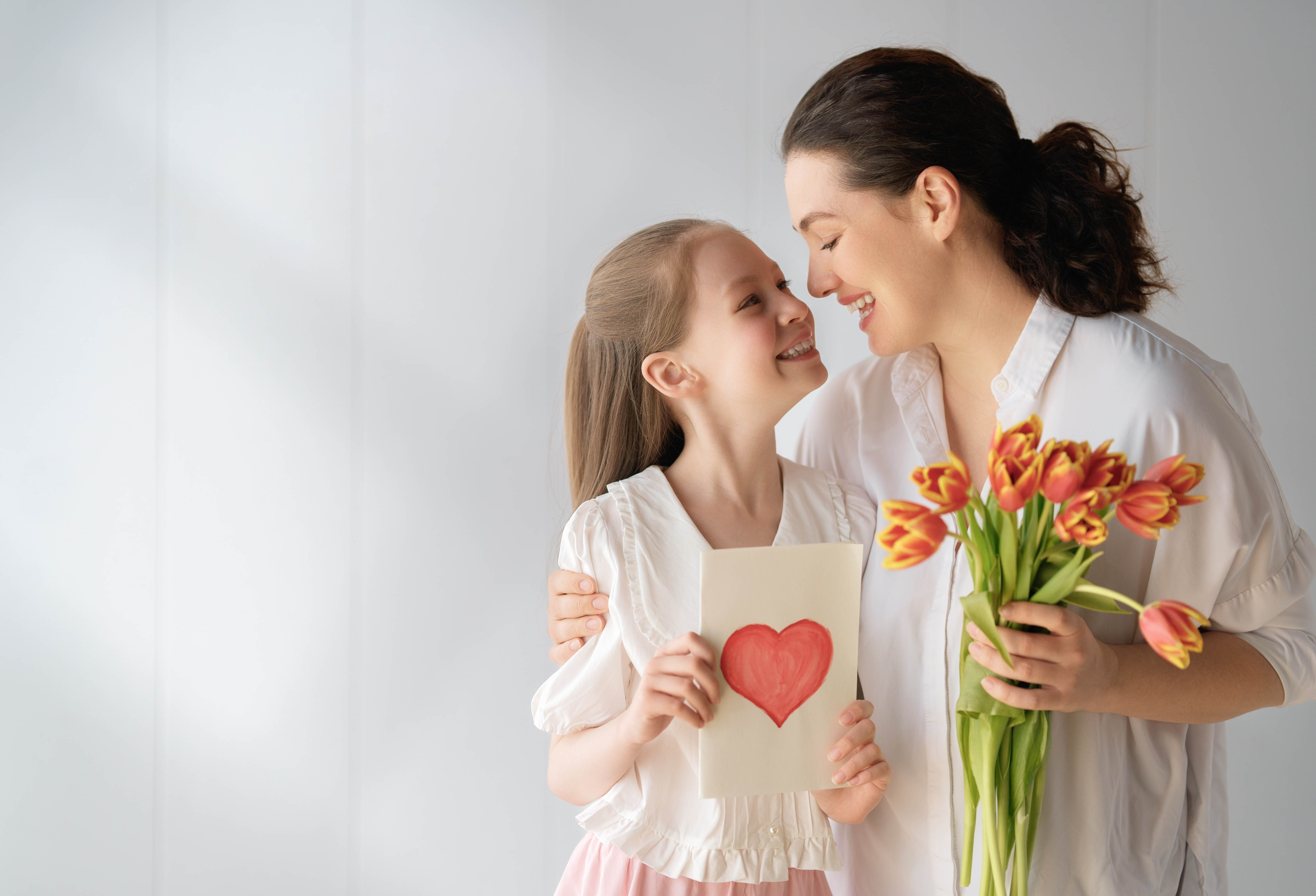 Mom and young daughter hugging and holding a bouquet of tulips